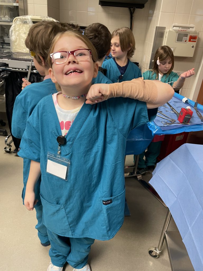 Female elementary student wearing green hospital scrubs smiling