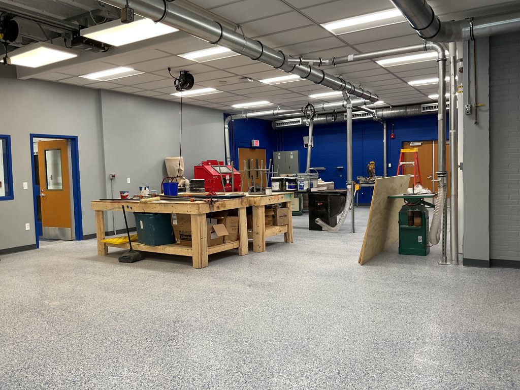 Empty classroom with two large wooden work benches and electrical equipment