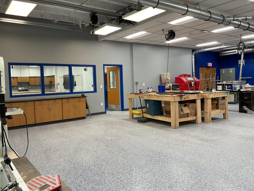 Empty classroom with two large wooden work benches, electrical equipment and cabinets