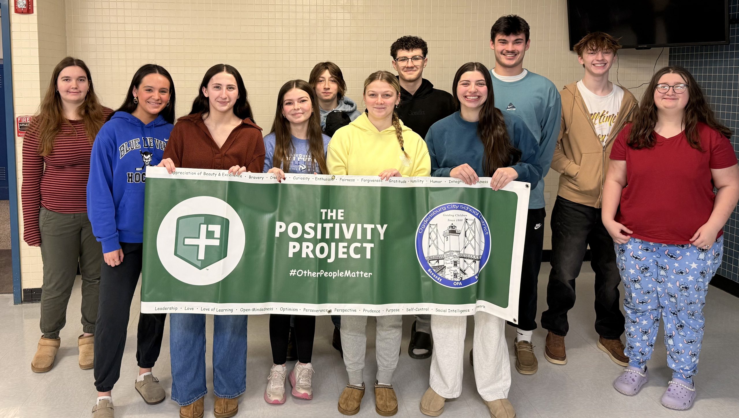 Small group of high school students smiling holding a sign