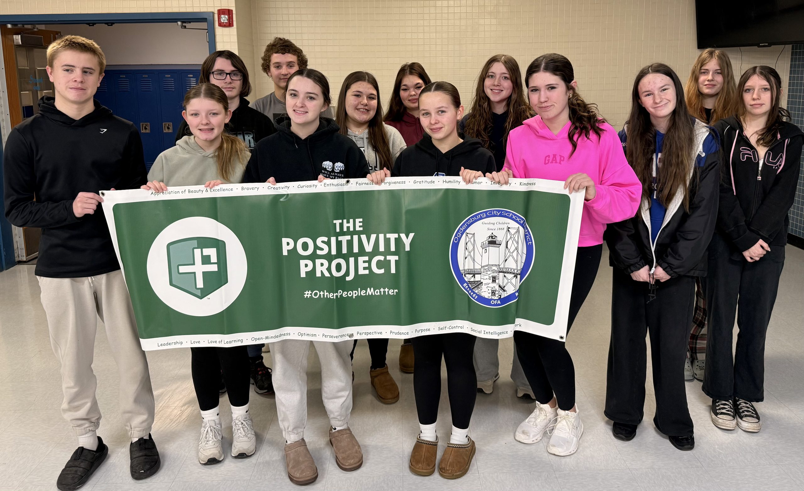 Small group of high school students smiling holding a sign