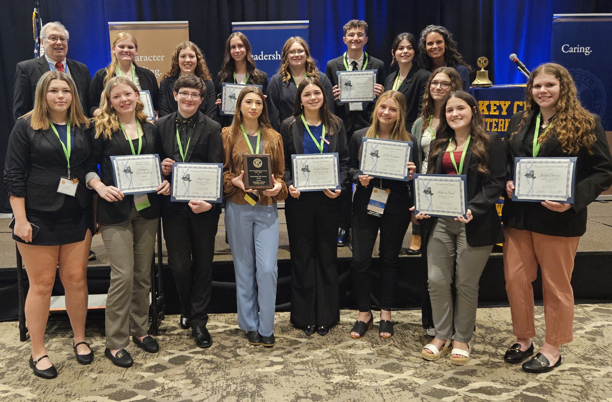 Small group of high school students and adults smiling holding certificates and a plaque