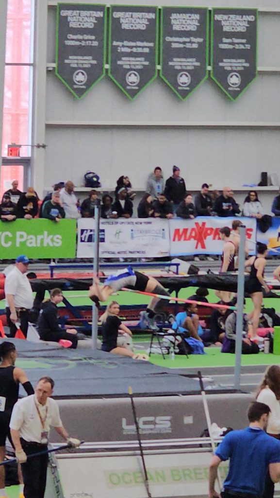 Female high school indoor track and field athlete competing in high jump