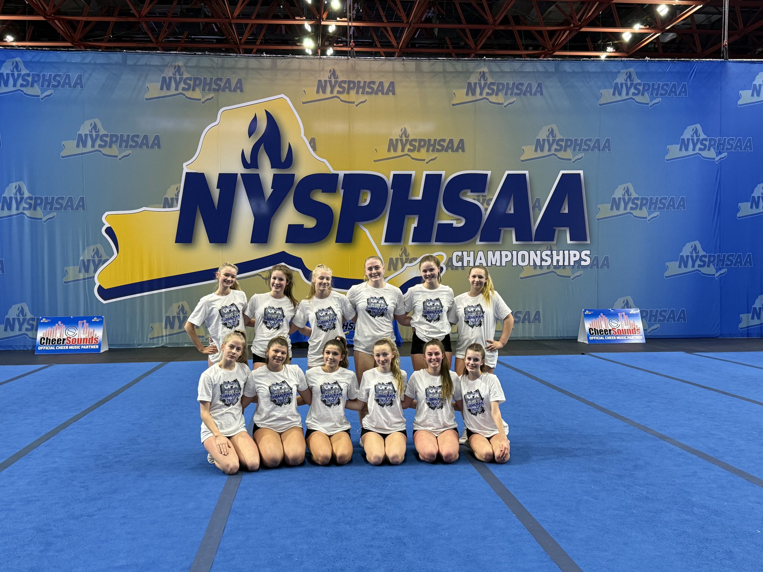 Small group of female high school cheerleaders wearing white at the New York State Public High School Athletic Association state championships