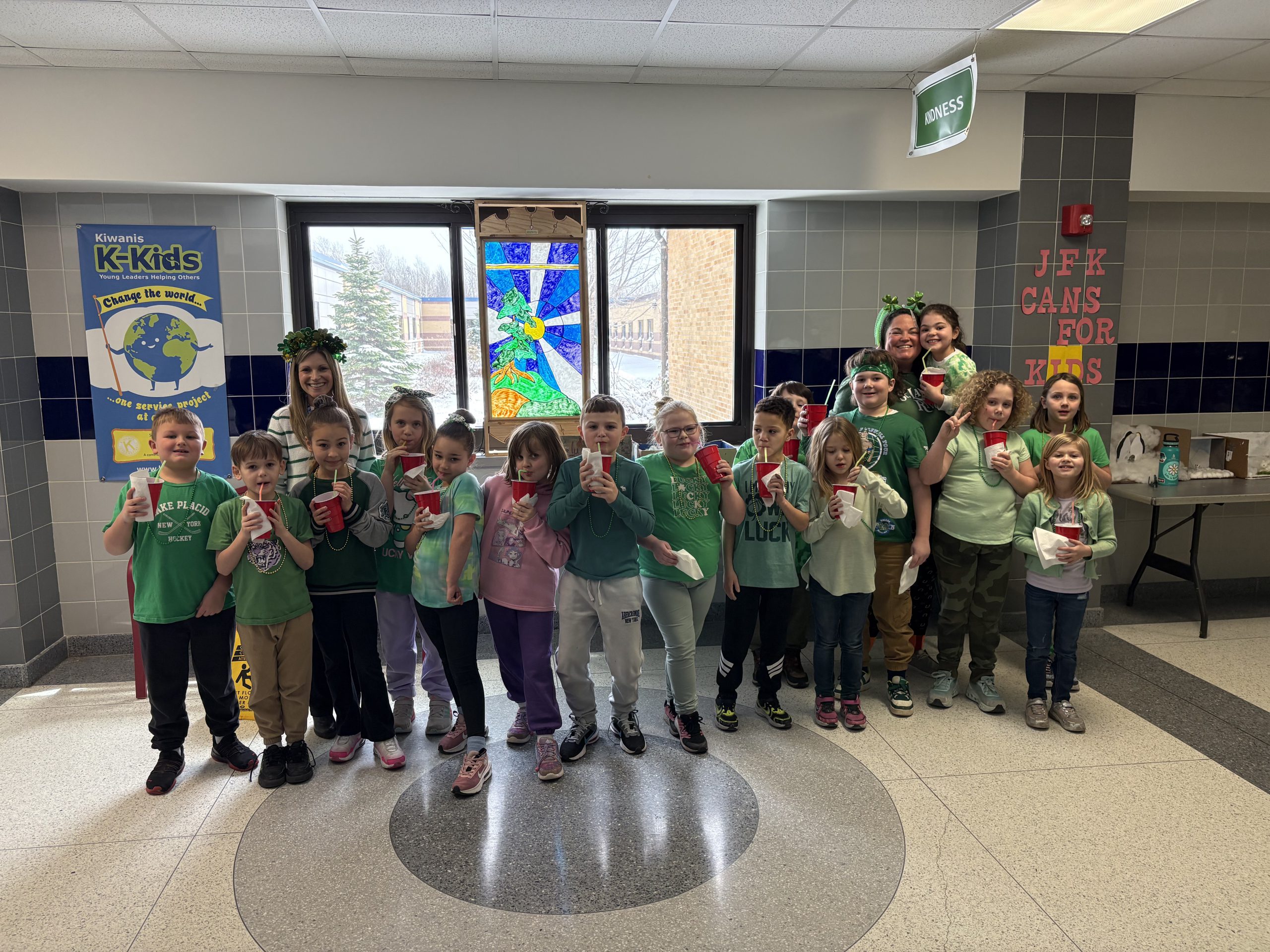 Small group of young students wearing green and holding cups in their hands