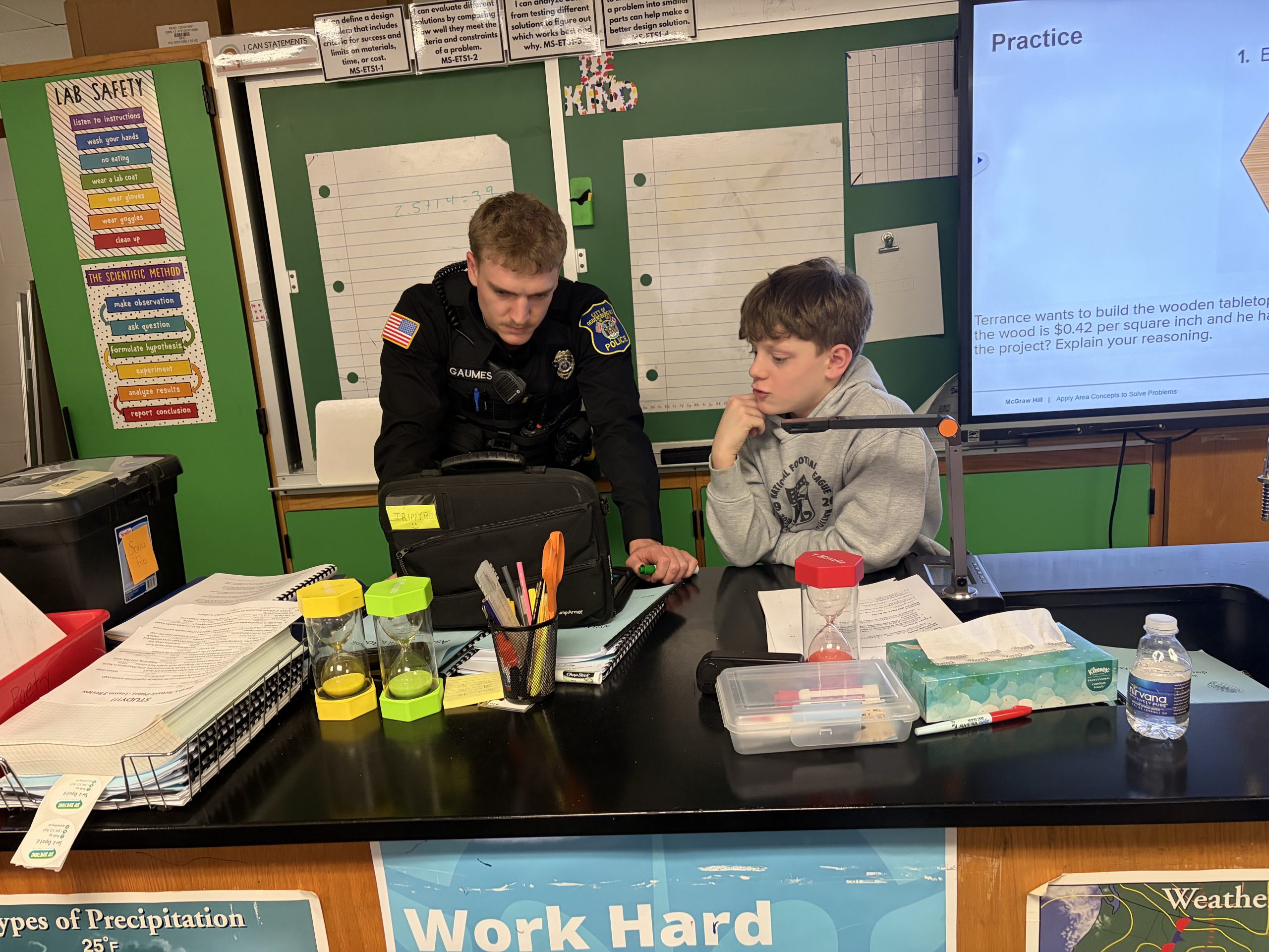 Young male student next to an adult male in a police uniform looking at a computer