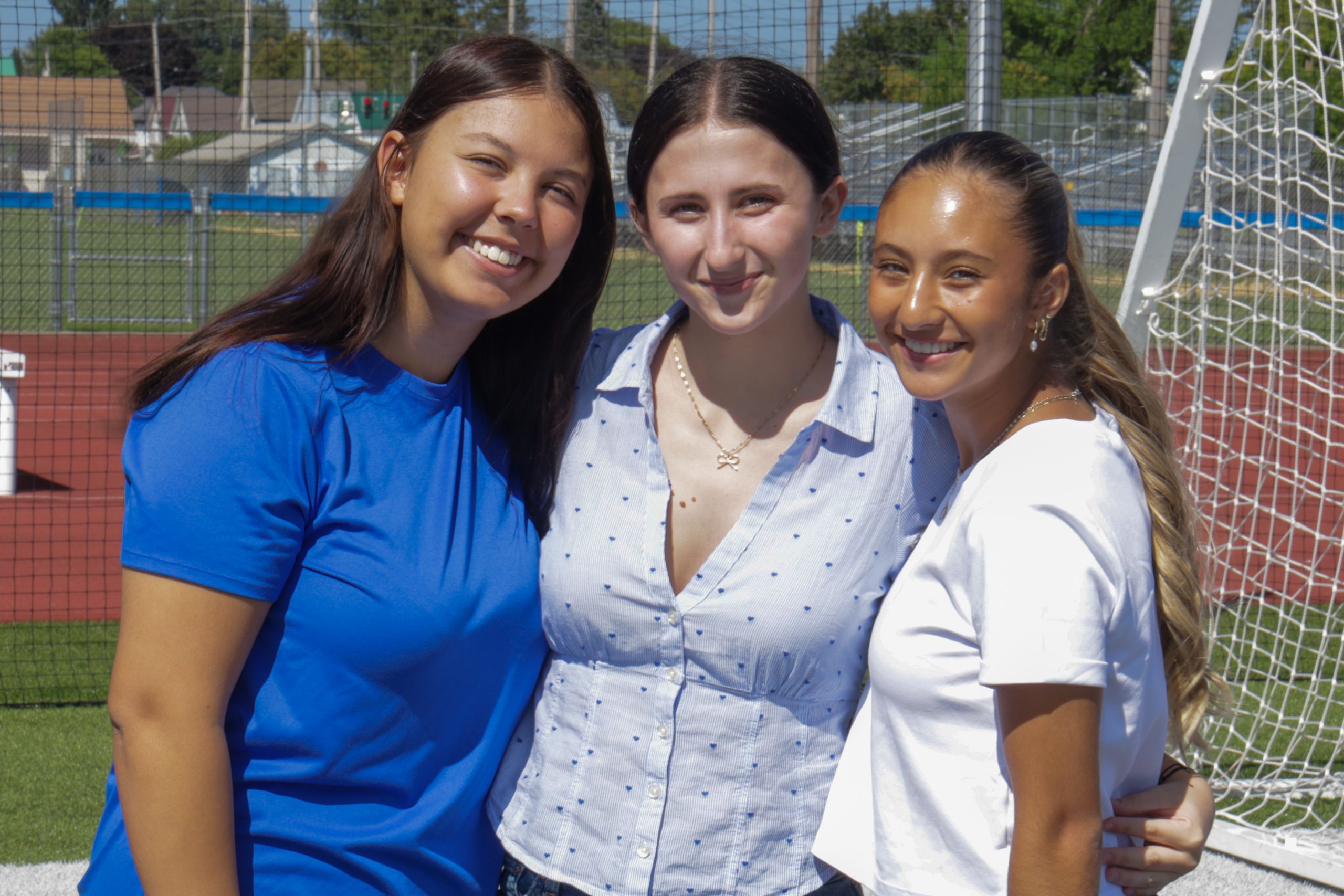 three students smiling outside